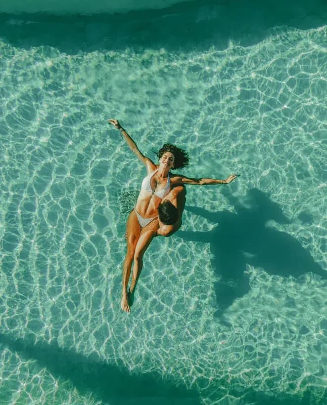 Aerial view of a couple relaxing in Mahekal Beach Resort's turquoise pool