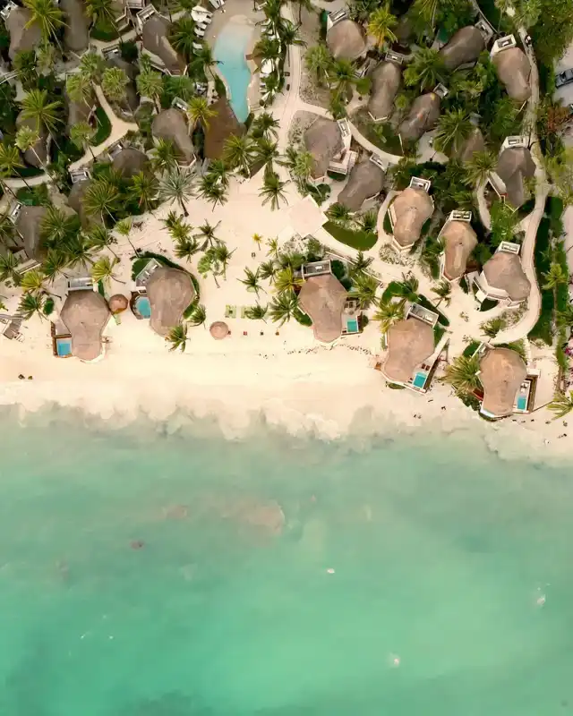 Aerial view of Mahekal Beach Resort's palapas next to the beach and turquoise sea